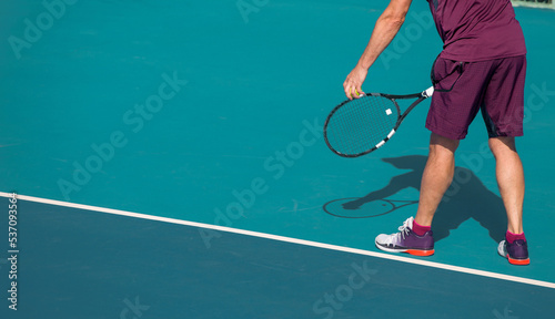 Tennis player playing tennis on a hard court on a bright sunny day © Павел Мещеряков
