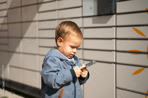 boy holding mobile phone near to Parcel locker Collecting parcel from shopping locker. Child Skans QR Code on Mobile phone Self-service Locker Cell with Bar code Reader Modern Shipping concept. photo