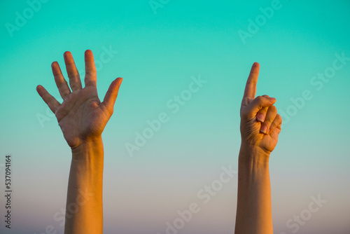 Woman hands showing or doing number seven gesture on turquoise summer sky background. Counting down, six fingers up concept idea.  photo