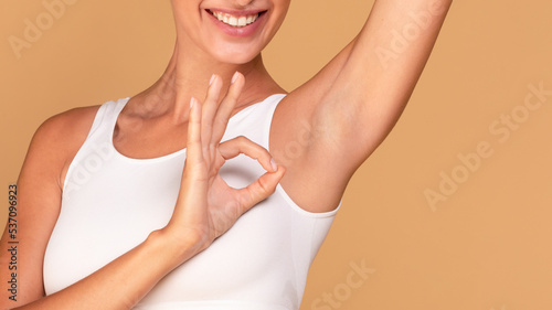 Happy lady showing her smooth armpit and ok gesture, enjoying underarm depilation result, panorama with copy space photo