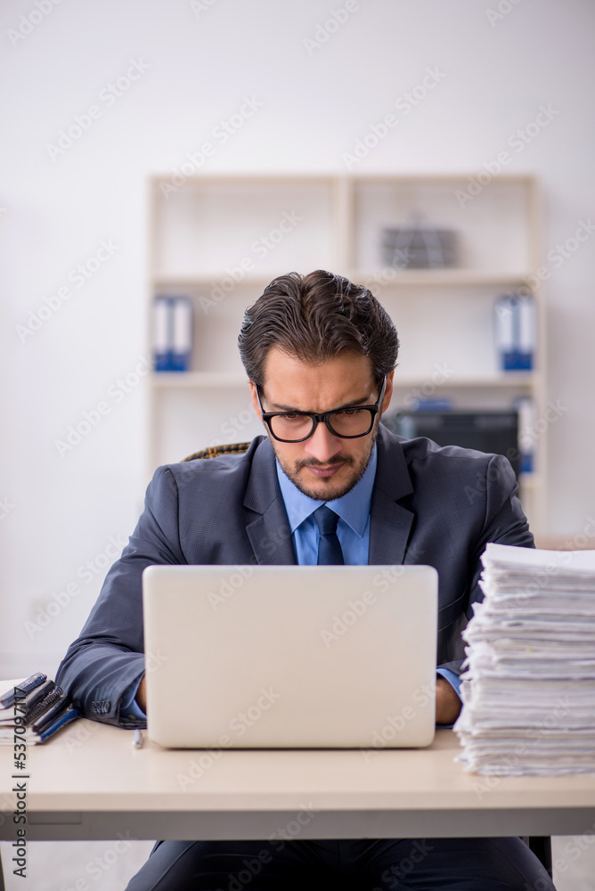 Young male employee and too much work in the office Young male employee and too much work in the office