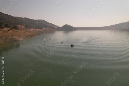 Aerial view of a lake with boats on it surrounded by a mountain range photo