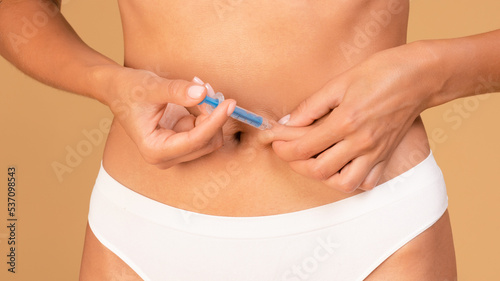 Unrecognizable woman in underwear doing injection in abdomen, holding medicine pen, closeup, panorama