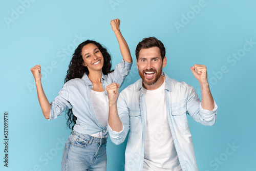 Surprised smiling millennial caucasian male with beard and arab lady in casual raising hands up