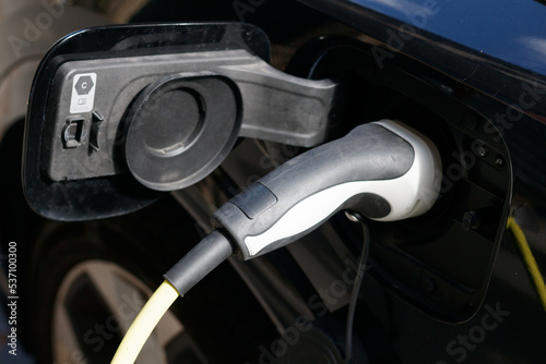 Close up on the charging wire of an EV while charging the battery. The charging station is located in a Parisian street