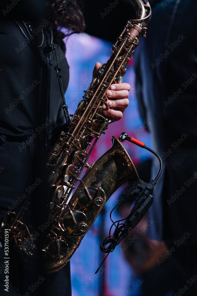 Naklejka premium Soprano saxophone in hands on a dark background. Alto sax musical instrument closeup
