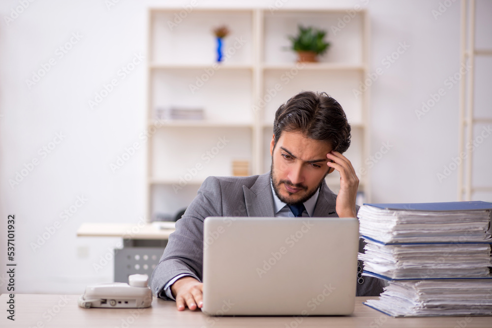 Young male employee and too much work in the office Young male employee and too much work in the office