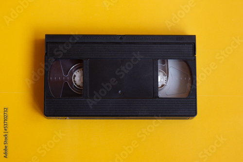 Old VHS video cassette on a yellow background. Outdated video technology. Background for a playlist of old movies