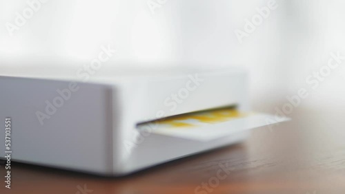 Wireless mini printer for smartphones. Process of printing photos with a portable printer at home. Small prints for a photo album.