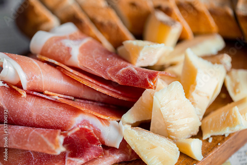 Wooden board with cheese and ham. Board with jamon and cheese. Aperitif on the board. Jamon with bruschetta and parmesan.Delicious appetizer for wine.Italian appetizer. Jamon and salami with cheese.