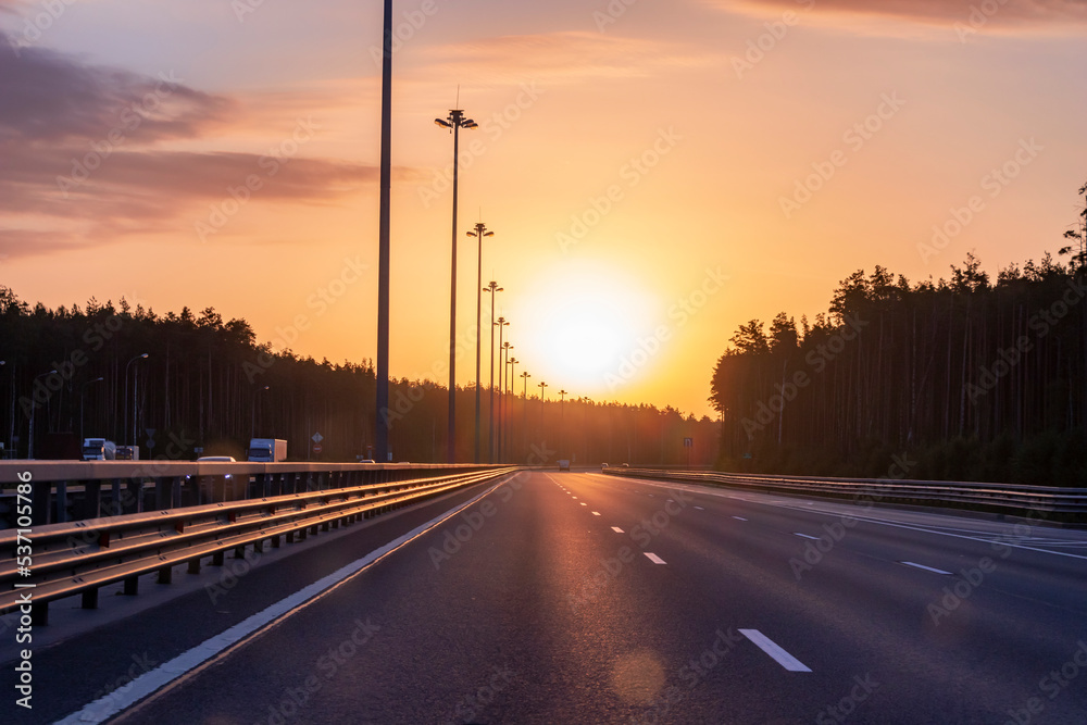 Highway in the glare of sunlight, illuminated by the sun. Urban landscape.