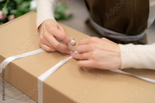 Woman hands wrapping a present in a box while working in the shop