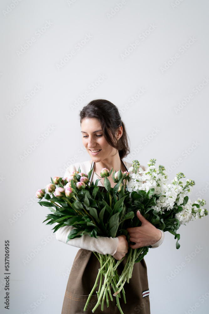 WOMAN florist EMBRACING a bunch of white and pink flowers on white background indoors WOMAN florist EMBRACING a bunch of white and pink flowers on white background indoors