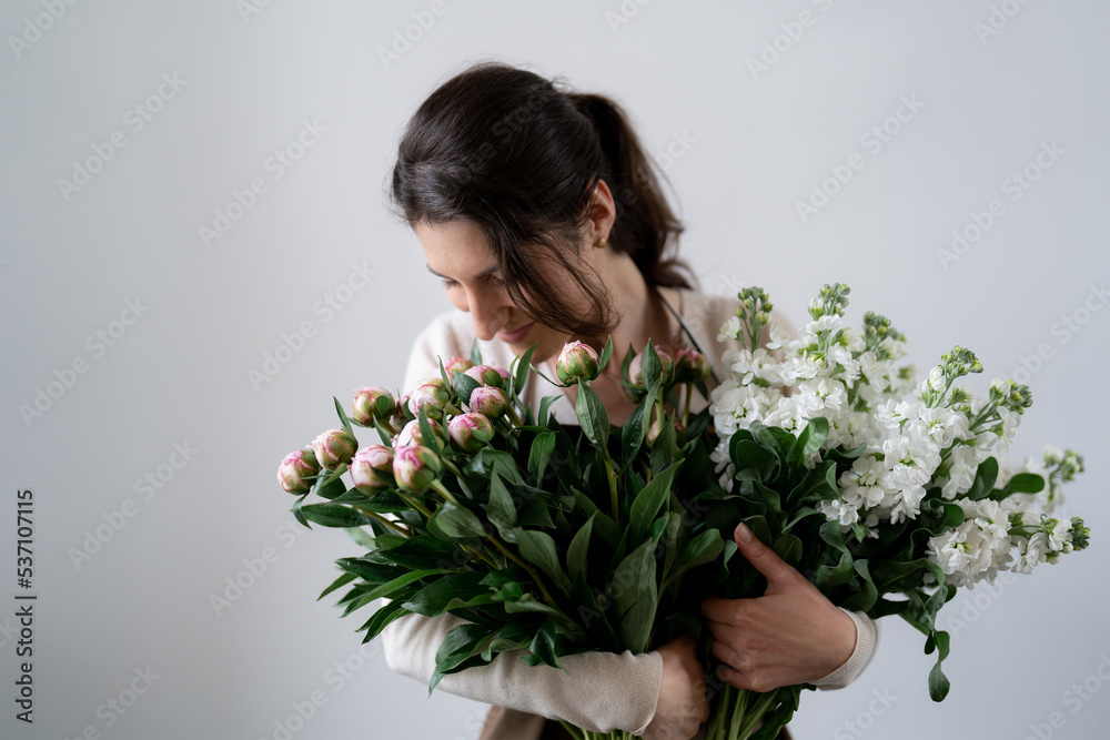 WOMAN florist EMBRACING a bunch of white and pink flowers on white background indoors WOMAN florist EMBRACING a bunch of white and pink flowers on white background indoors