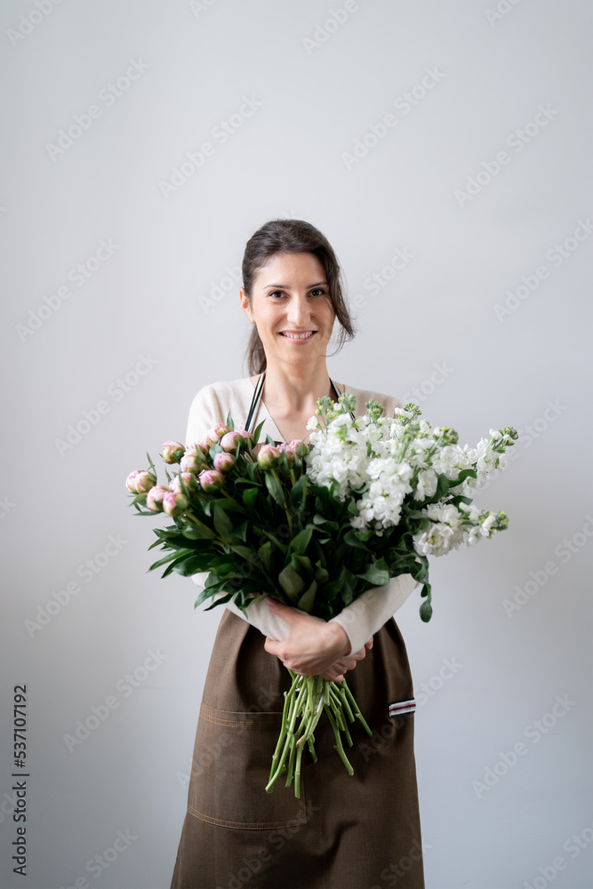 WOMAN florist EMBRACING a bunch of white and pink flowers on white background indoors WOMAN florist EMBRACING a bunch of white and pink flowers on white background indoors