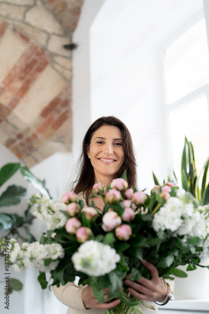 Positive woman holding a huge bouquet of flowers in her office. Birthday present smile. Positive woman holding a huge bouquet of flowers in her office. Birthday present smile.