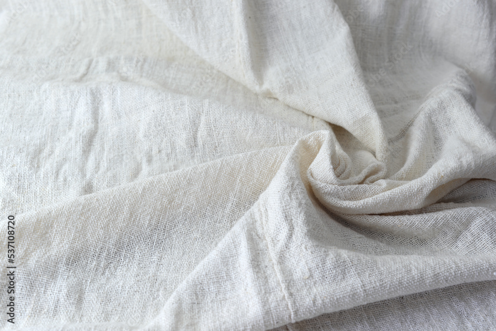 An image of the top corner of a pile of white cotton fabric, wrinkled, wavy, for use in the background.
