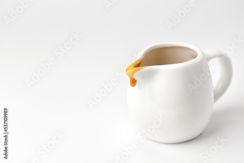 Foto Drop of liquid caramel on a white gravy boat on grey background.
