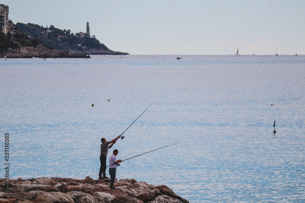 Nice, France - 29.09.2022 : Fishermen in Nice fishing on the shores of the Mediterranean Sea