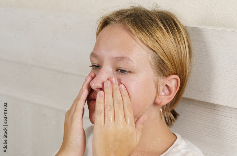 A teenage girl massages her face with her hands with cream A teenage girl massages her face with her hands with cream