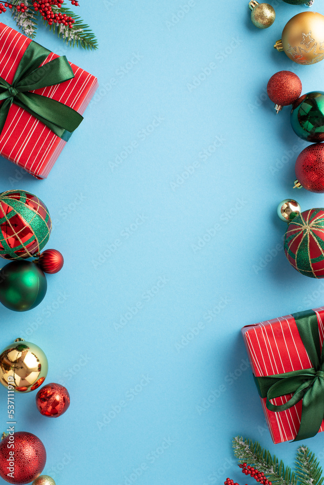 Christmas concept. Top view vertical photo of present boxes with ribbon bows red green gold baubles pine branches and mistletoe berries on isolated pastel blue background with copyspace