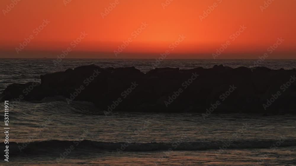 Waves rolling at dusk in slow motion as the sky glows orange along the California coast. Waves rolling at dusk in slow motion as the sky glows orange along the California coast.