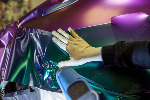 Fotografía A specialist in wrapping a car with chameleon-colored vinyl film in the process of work