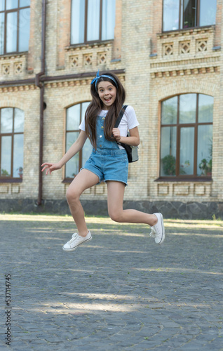 happy denim girl with backpack jumping outdoor