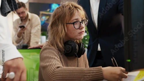 Caucasian woman artist designer draws on a computer tablet 3d models for games. Director of the company comments on the work and gives instructions for correction.