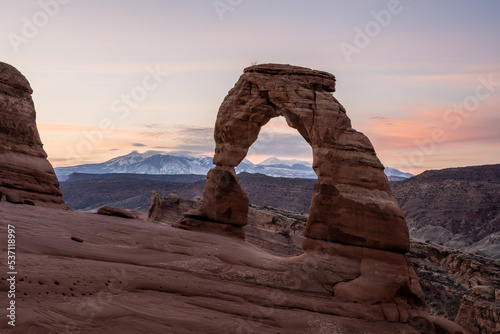 Delicate Arch Stands Tall With Pastel Clouds And La Sal Mountains at sunrise