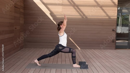 Beautiful strong muscular woman doing stretching on mat on terrace outdoors. Healthy young adult girl in sportswear stretch alone. Fit thin gimnast doing yoga, training on mat. Slow motion
