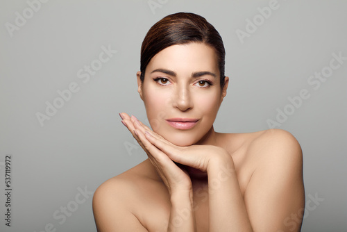 Beauty and Skin Care Concept. Beautiful natural woman with clean healthy luminous skin. Beauty portrait on grey background with copyspace