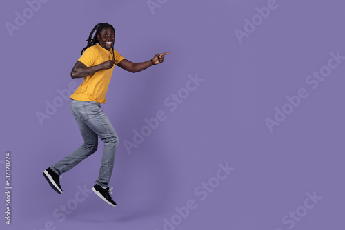 Excited african american young man running towards copy space © Prostock-studio