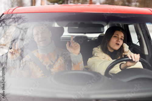 Portrait of carefree young couple singing in car while driving to winter vacation together photo