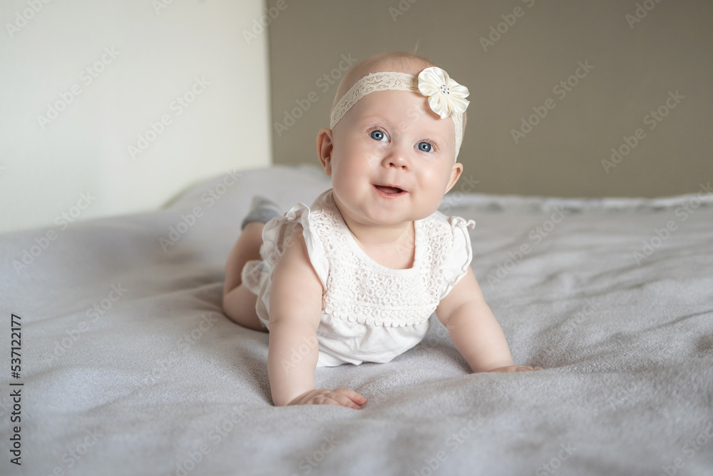 Portrait of a beautiful little baby girl lying on her stomach and looks away with admiration.