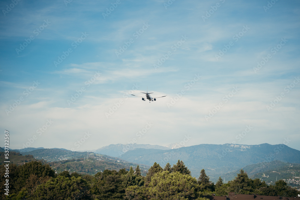 the plane is landing, flying low over the forest