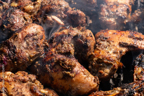 Grilling traditional Jamaican spicy jerk chicken with over charcoal fire. photo