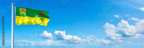 Saskatchewan - Canada flag waving on a blue sky in beautiful clouds - Horizontal banner 