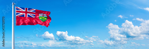 Ontario - Canada flag waving on a blue sky in beautiful clouds - Horizontal banner
