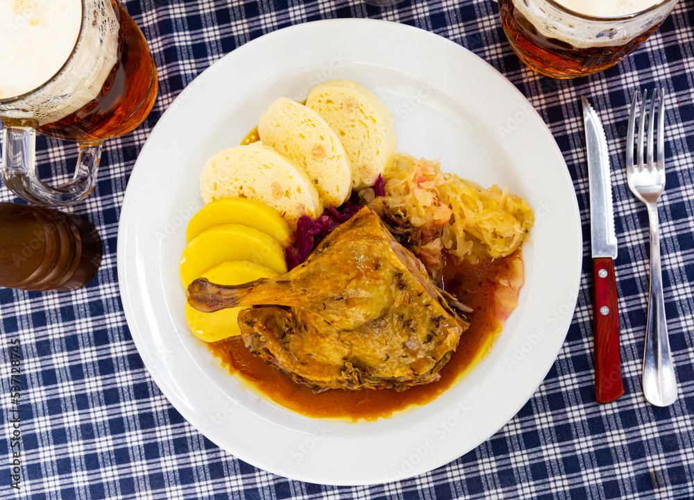 Juicy roasted duck leg served with red and white cabbage and Czech dumplings on plate