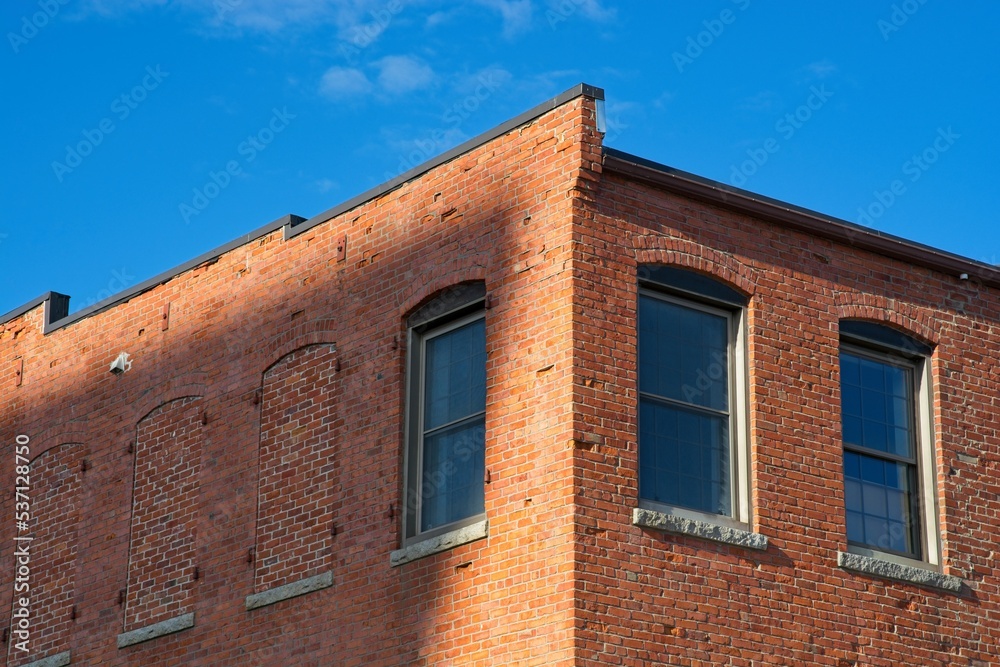 Brick mill building corner roofline against bright blue sky in Haverhill downtown