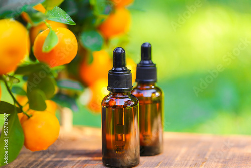 Mandarin oil.tangerine essential oil.Natural organic pure oil. brown bottles with oil on a brown wood background and tangerines with green leaves.Organic natural eco cosmetics.