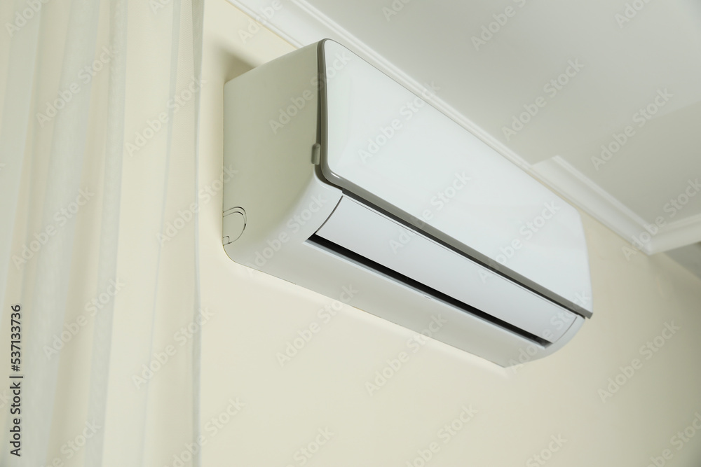 Modern air conditioner on white wall indoors Modern air conditioner on white wall indoors