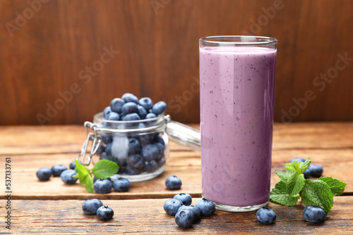 Glass of blueberry smoothie with mint and fresh berries on wooden table. Space for text
