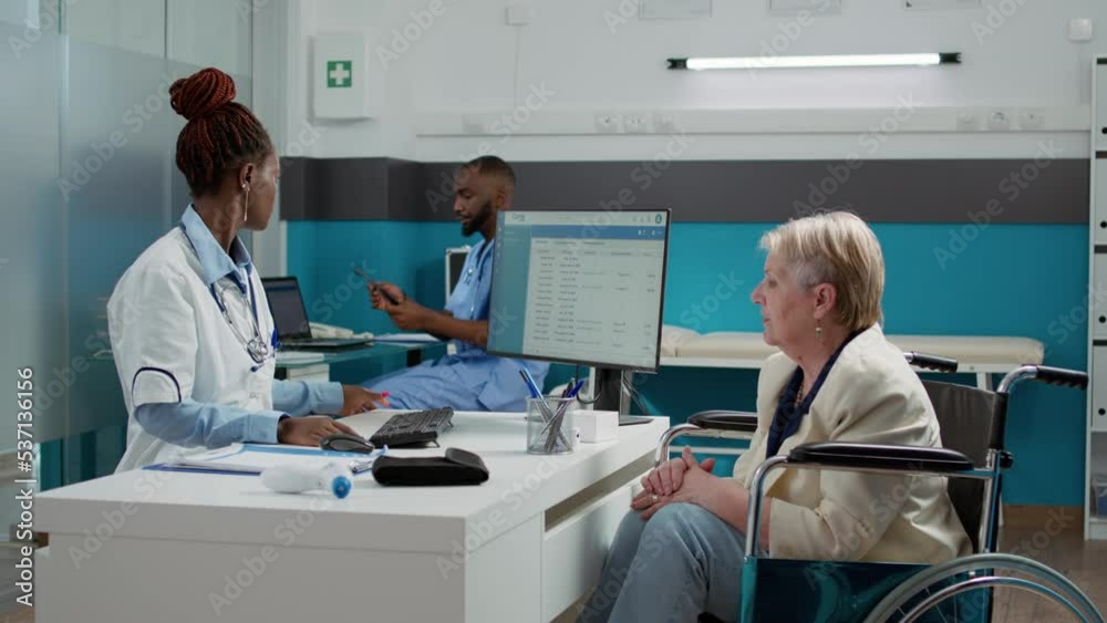 Woman with physical impairment analyzing x ray scan with doctor at checkup visit in medical cabinet. Old patient wheelchair user looking at bones radiography diagnosis results, healthcare. Woman with physical impairment analyzing x ray scan with doctor at checkup visit in medical cabinet. Old patient wheelchair user looking at bones radiography diagnosis results, healthcare.