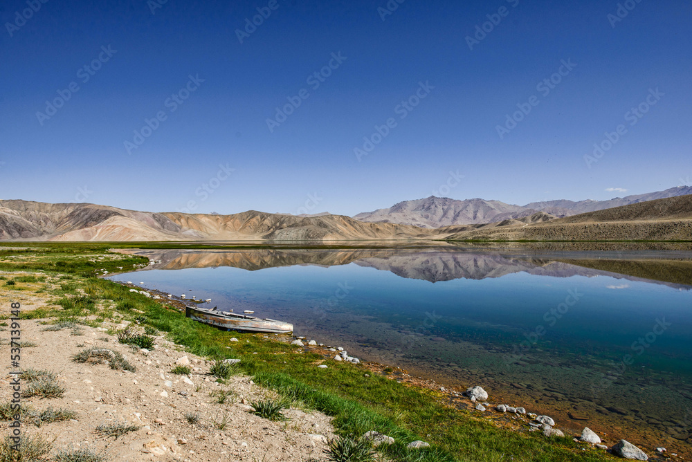 Reflecting rainbow mountains on Lake Bulunkul, Pamir Highway, Tajikistan