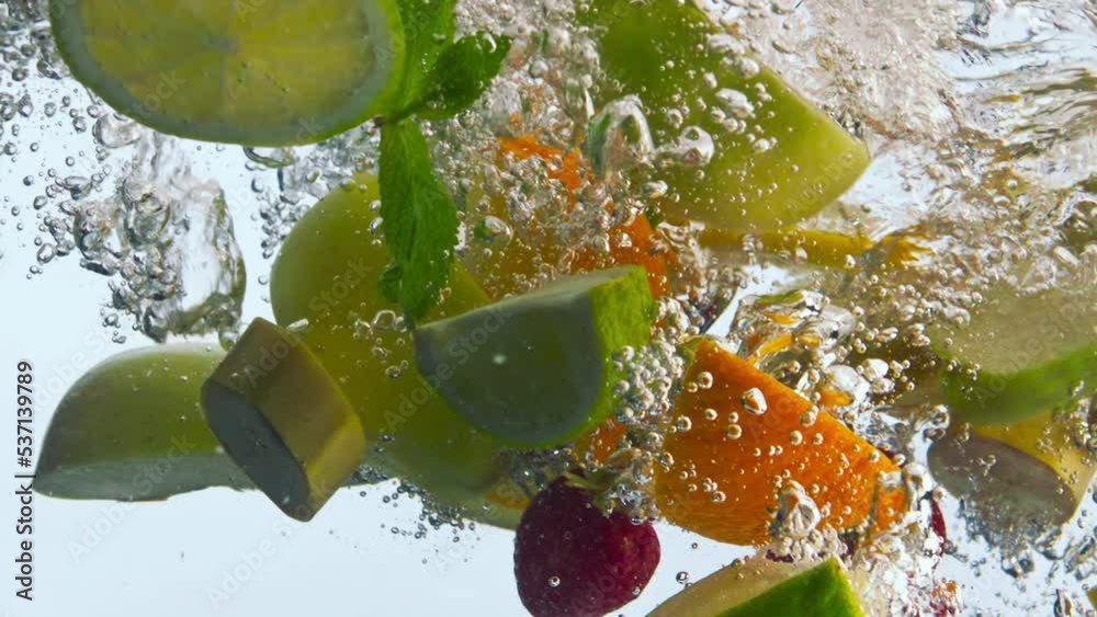 Juicy fruits falling water in super slow motion. Organic ingredients floating.
