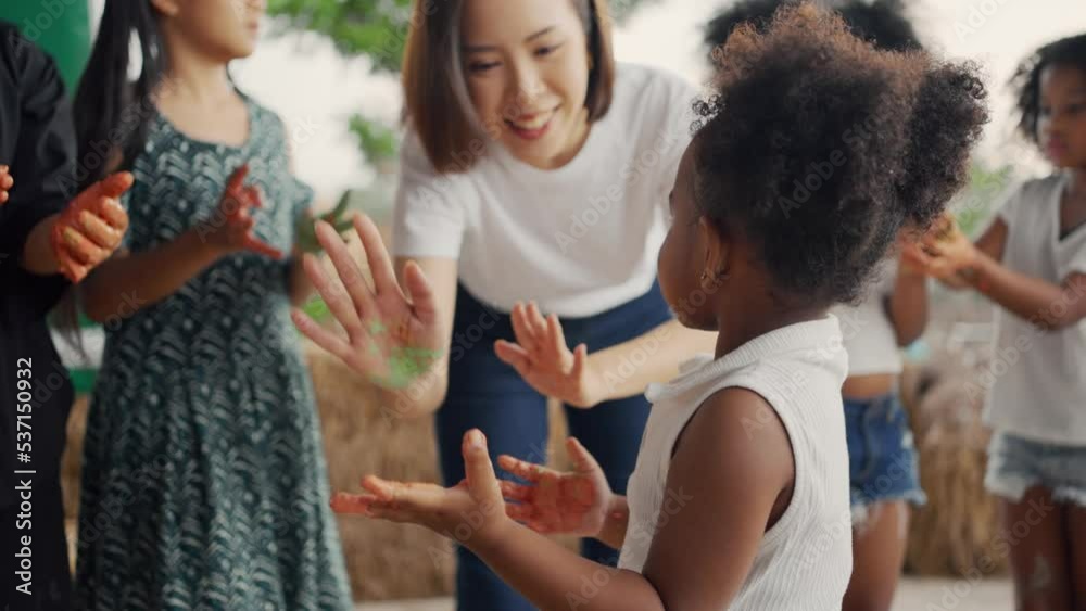 Group of children playing colourful water colours and colour stain on hand and dress. Happy children playing and painting water colour in class at school.