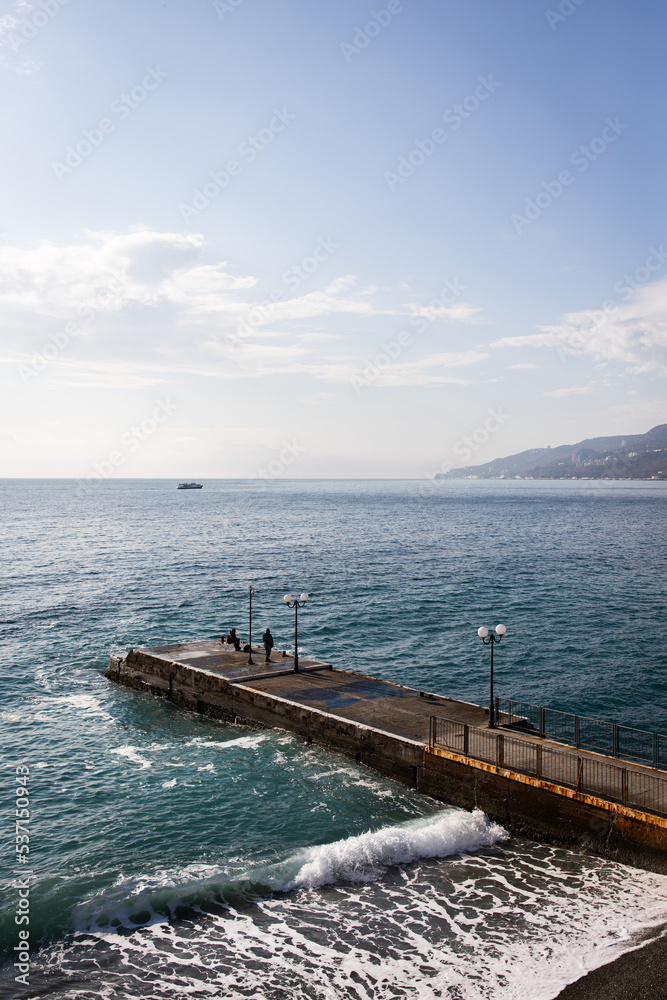 Winter sea, waves crashing on the pier in Yalta. Vertical photo.