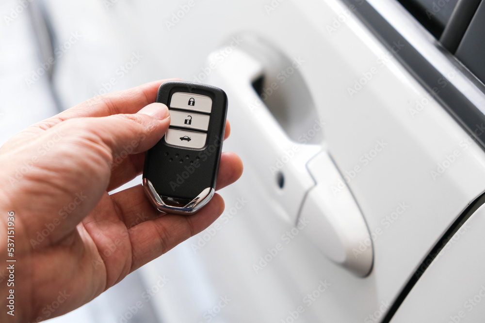 Man hand holding the car remote, he push the remote control to open the car door Man hand holding the car remote, he push the remote control to open the car door
